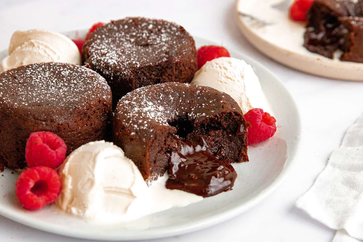Three chocolate lava cakes on dessert plate with ice cream.