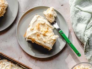 Overhead view of a gray plate of coconut cake with a fork next to a green cloth napkin