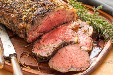 A prime rib on a carving board with several slices cut