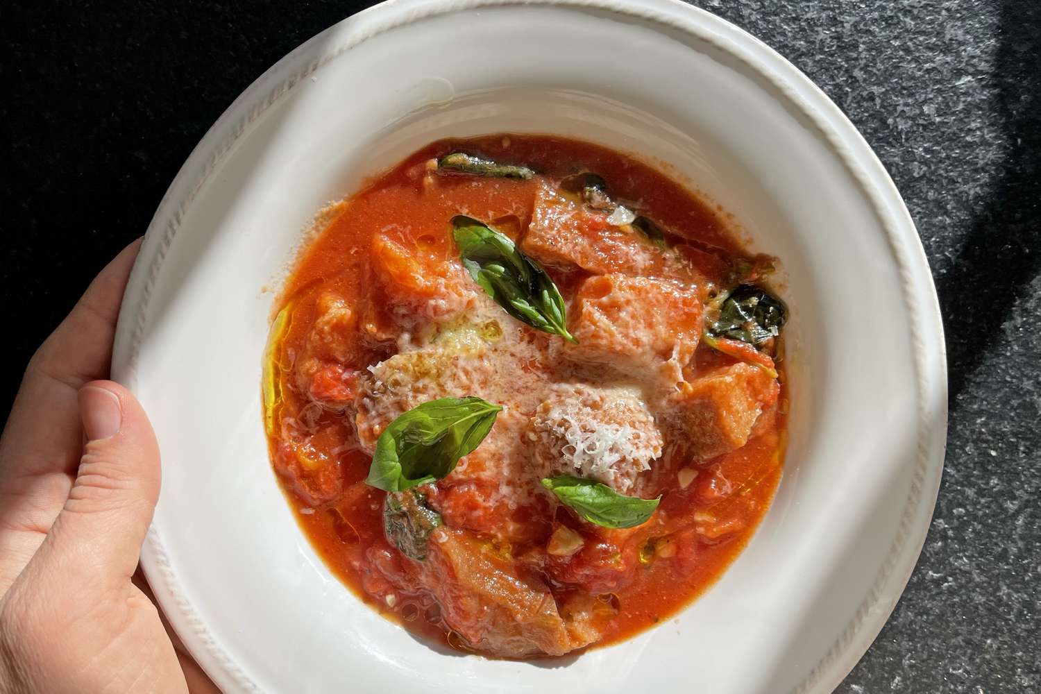 Bowl of tomatobased soup with bread and basil leaves