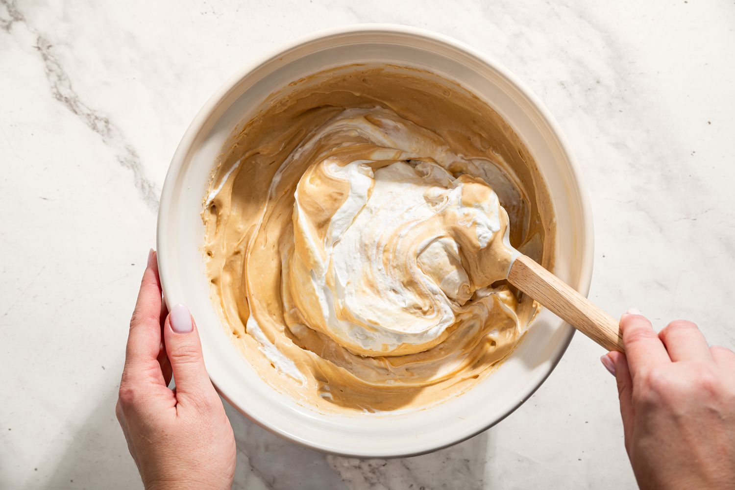 hand stirring whipped cream into peanut butter mixture in a bowl for No-Bake Fluffernutter Pie