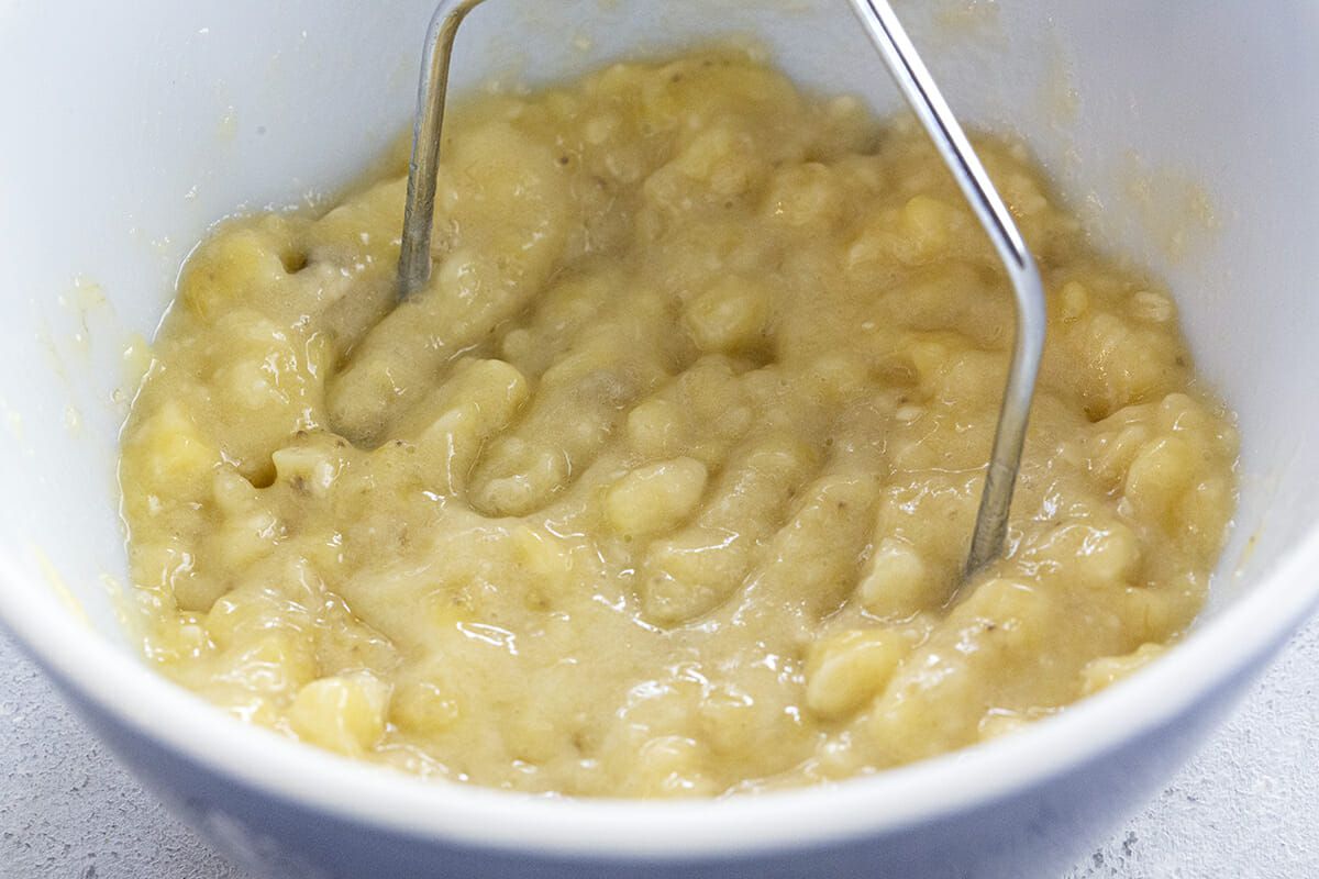 Bananas mashe in a white bowl.
