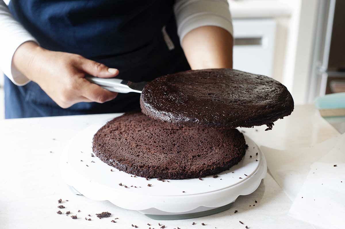 How to make Black Forest Cake by slicing the chocolate cake horizontally and lifting the top half off and setting aside.
