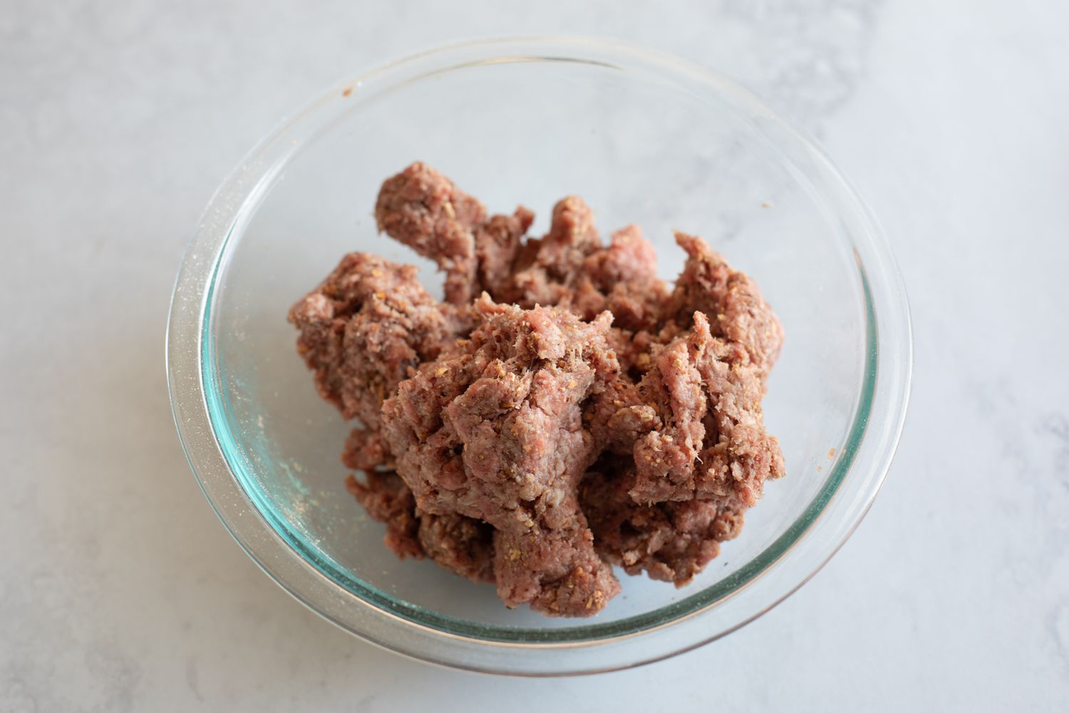 Mixture for a ground beef and mushroom recipe in a glass bowl.