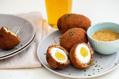 Scotch eggs in half on a plate with honey mustard dip.