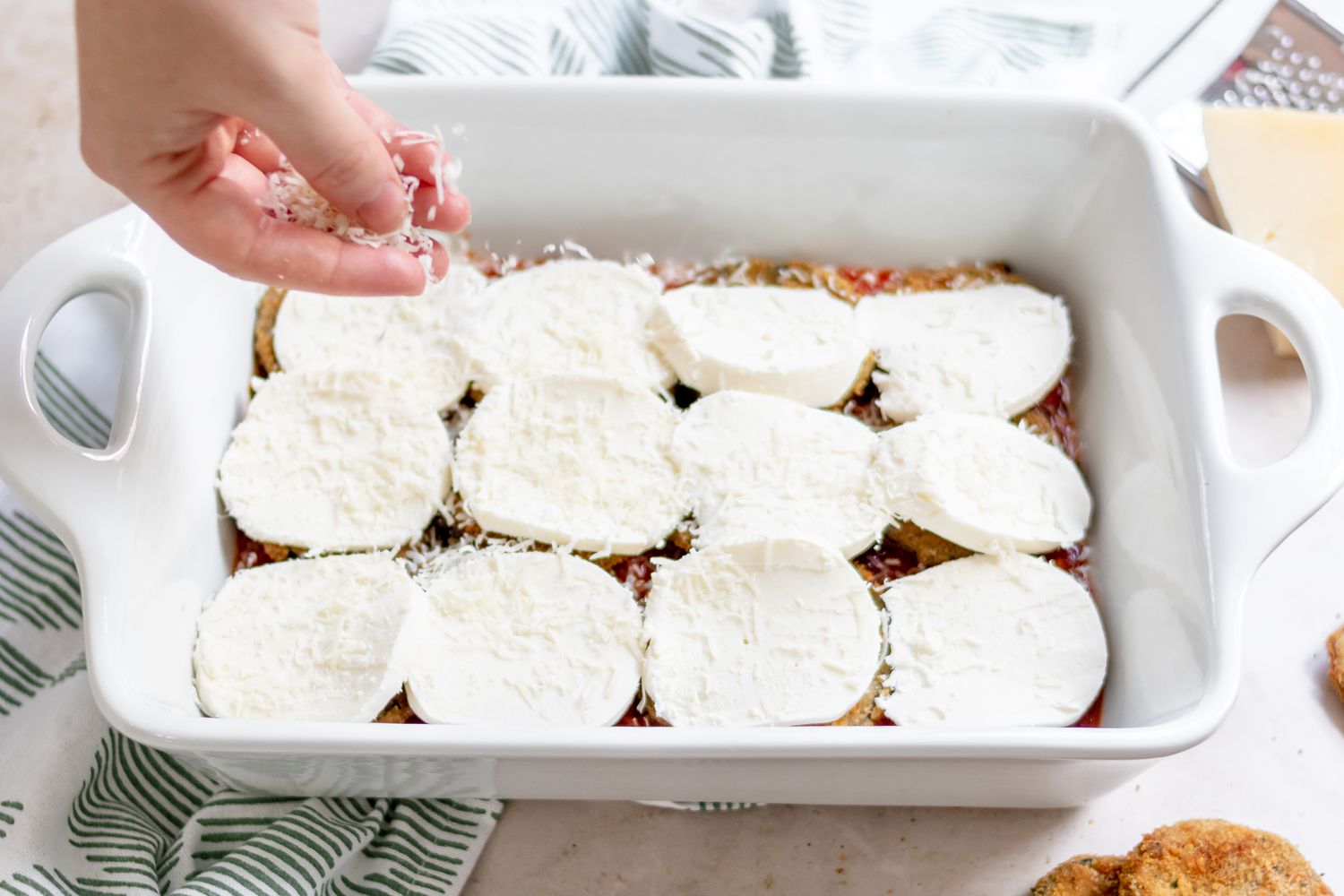 Topping eggplant with fresh slices of mozzarella in a casserole dish