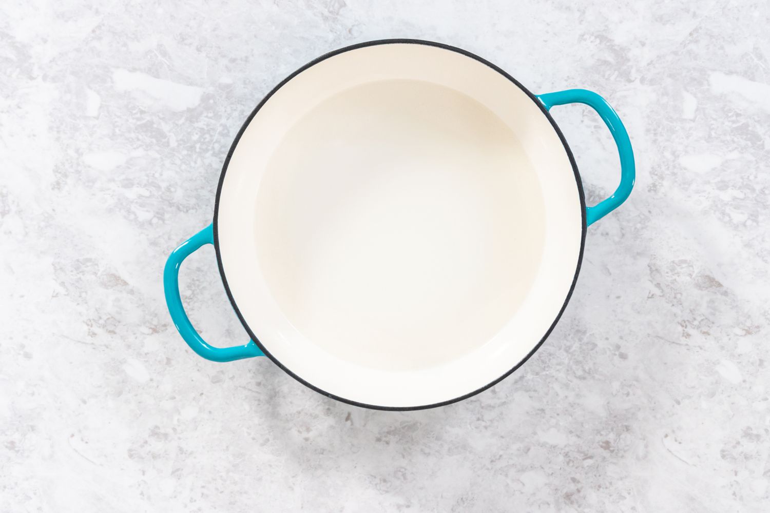 A white pot with blue handles on a light surface