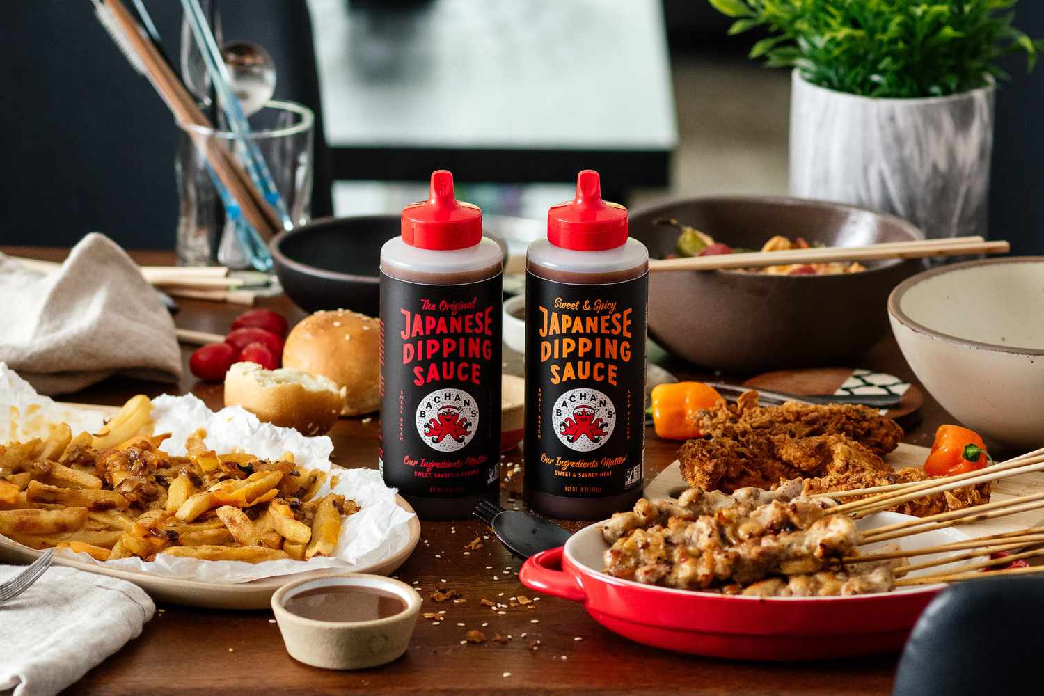 A food spread and two Bachan's dipping sauce bottles on a table