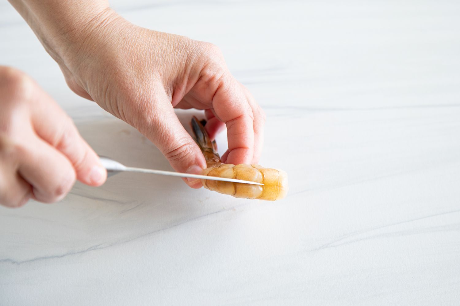 Using a knife to show how to clean a shrimp.