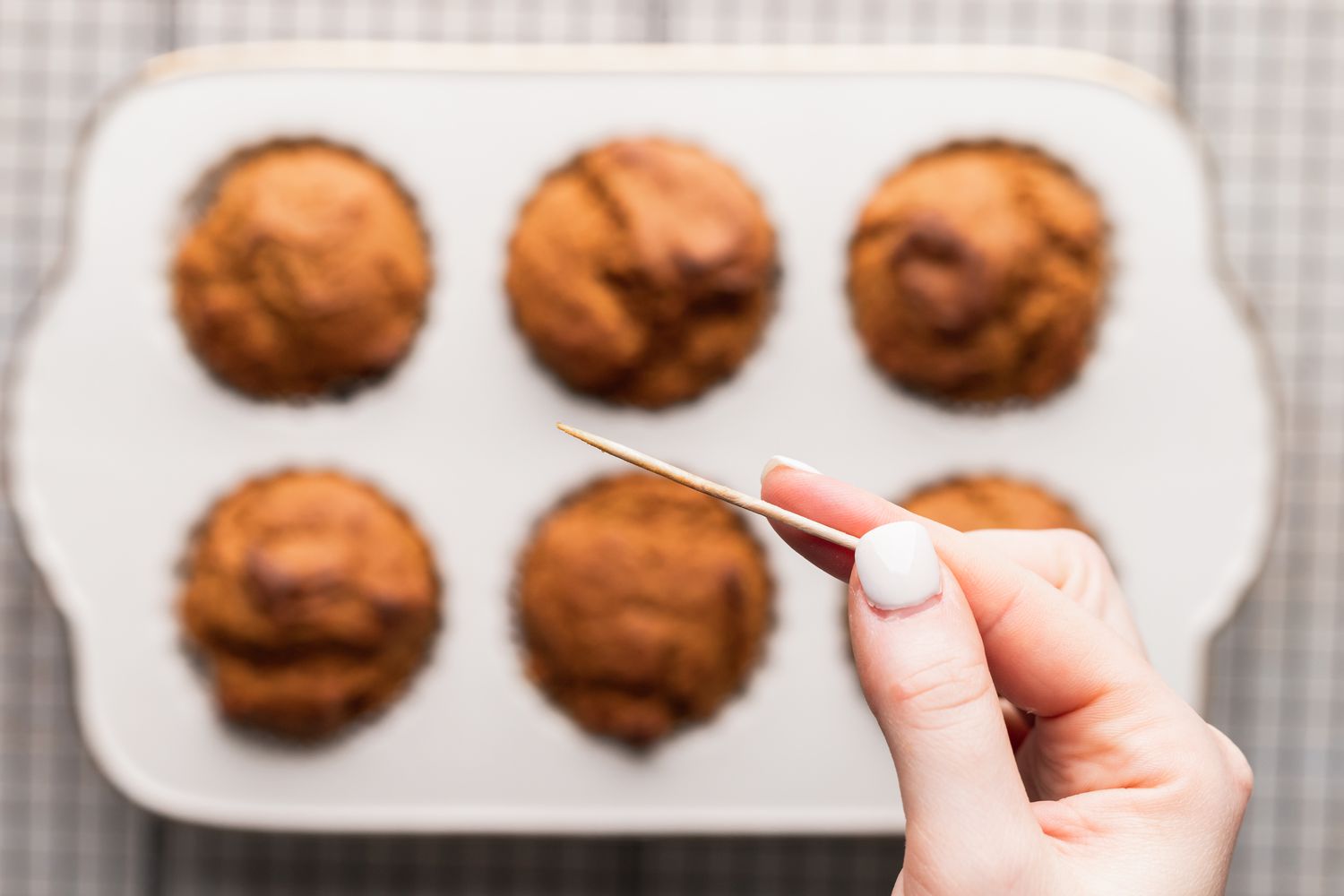 Checking for doneness with a toothpick to show how to make pumpkin muffins.