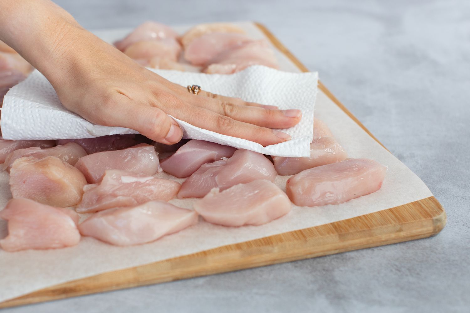 Patting chicken breast pieces dry for breaded chicken breast recipes.
