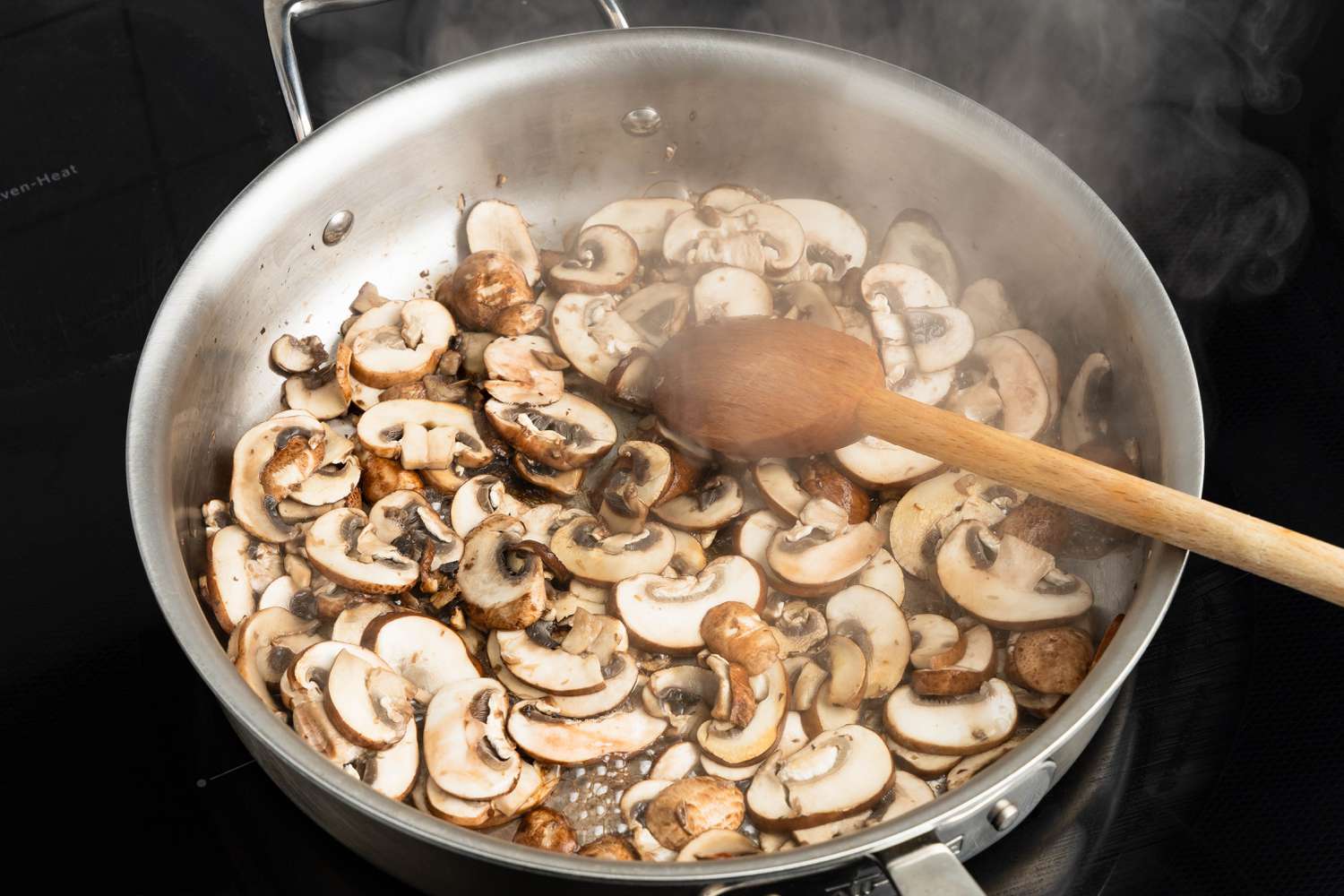 Sliced mushrooms stirred in a hot skillet over the stove for Johnny Marzetti casserole recipe