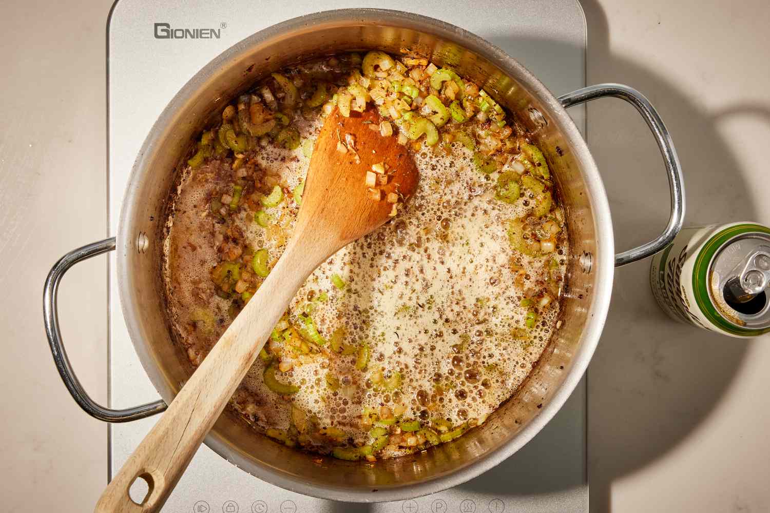 Overhead view of a saucepan with a wooden spoon after adding the onions and celery for Wisconsin Stuffing recipe