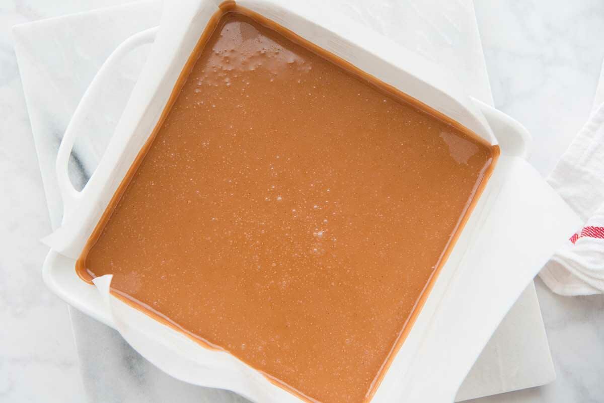 Soft Caramel Candy Recipe poured into a square pan lined with parchment paper.