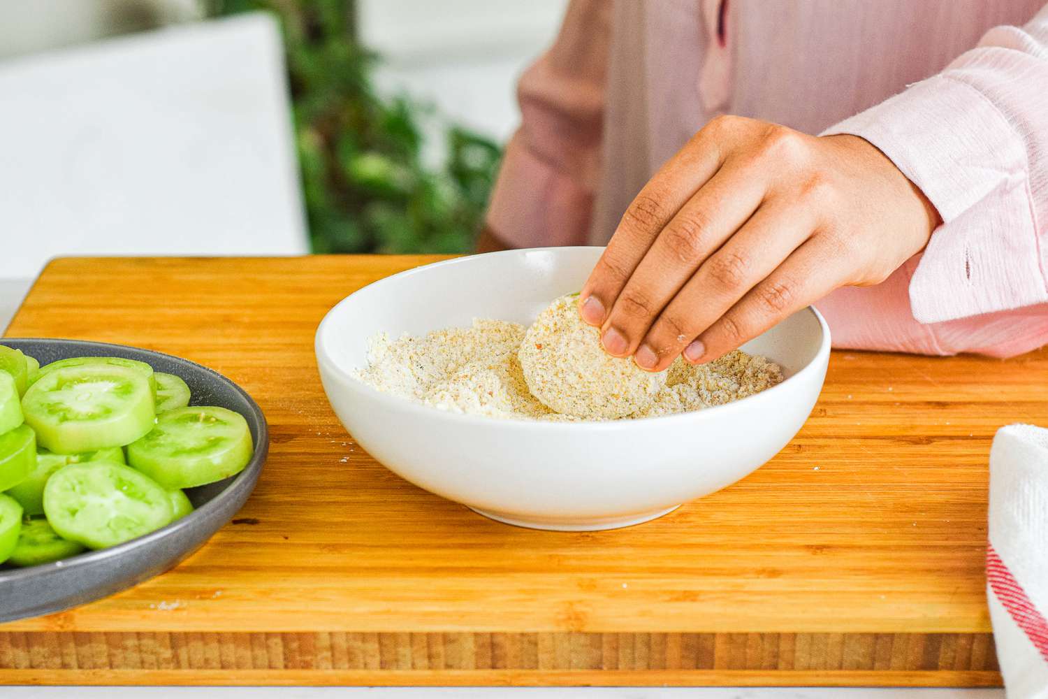 Dipping fried green tomato and breading.