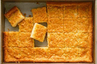 Overhead shot of butter mochi baked in a rectangular baking dish, cut into squares with some pieces taken out