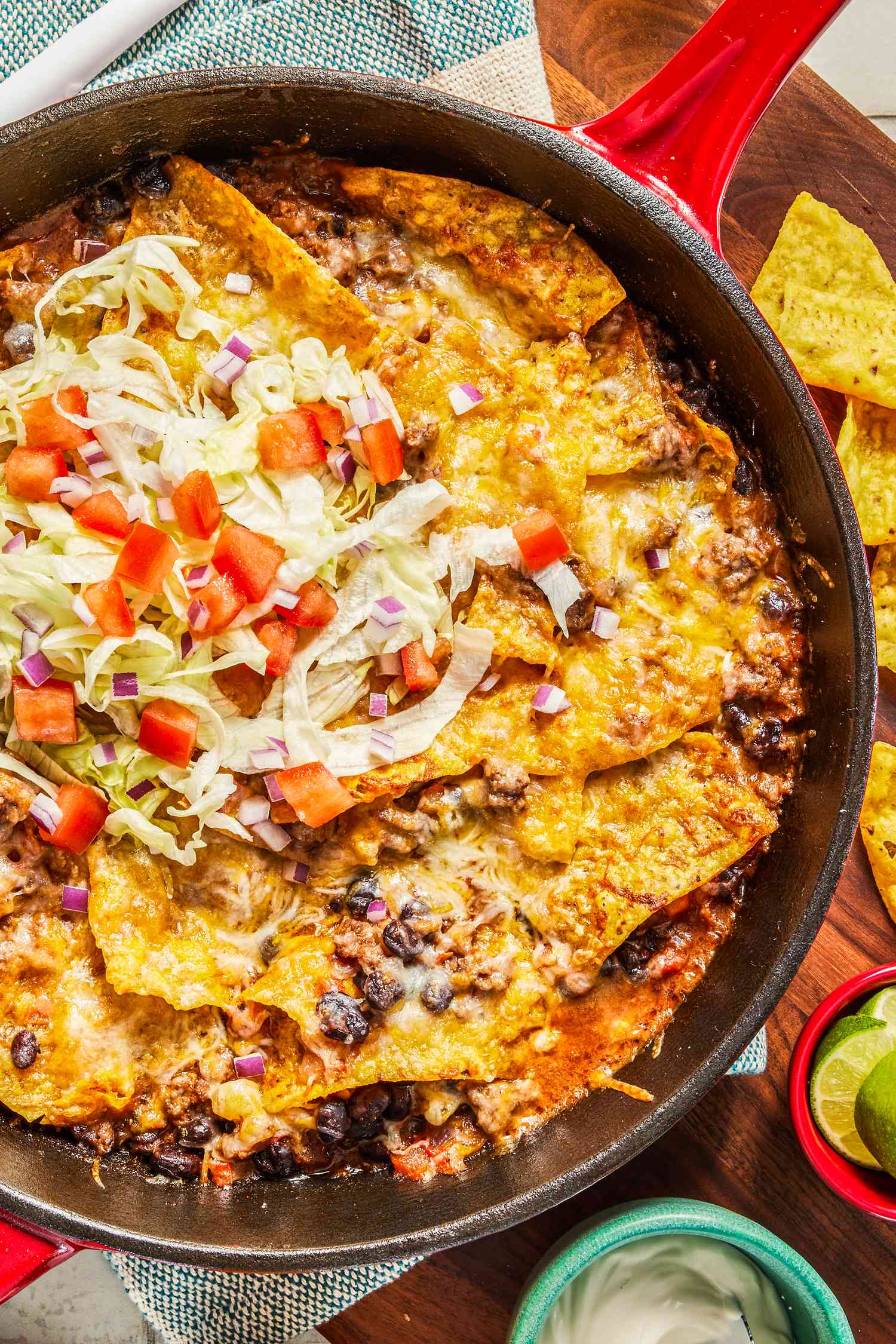 easy taco casserole in a skillet at a table setting with a tray of chips and a bowl of sour cream