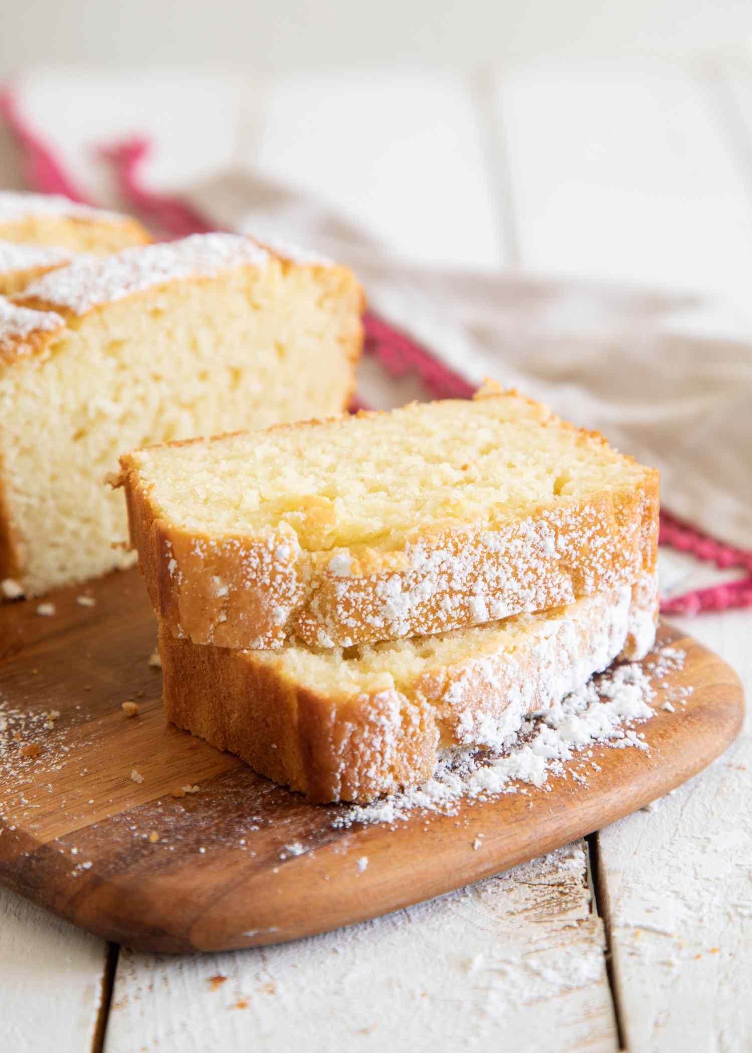 Stacked slices of Simple Yogurt Cake on a wooden paddle.