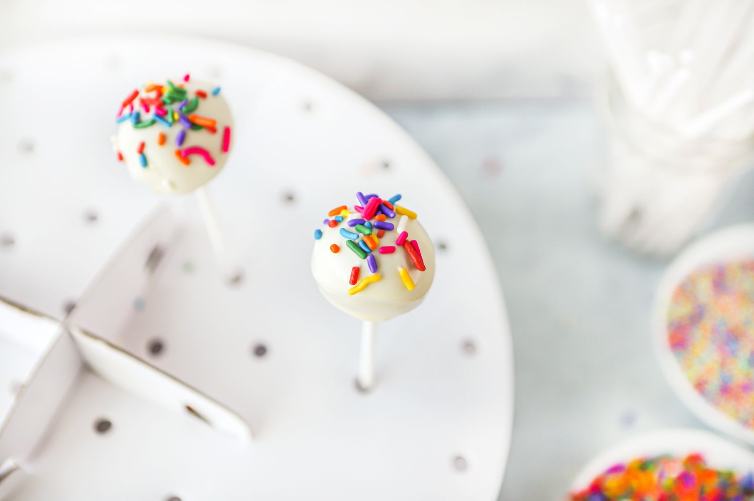 Cake Pops on a Stand with Holes Surrounded by Sticks and Sprinkles