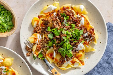 A plate of Turkish pasta topped with ground meat, yogurt, and fresh herbs