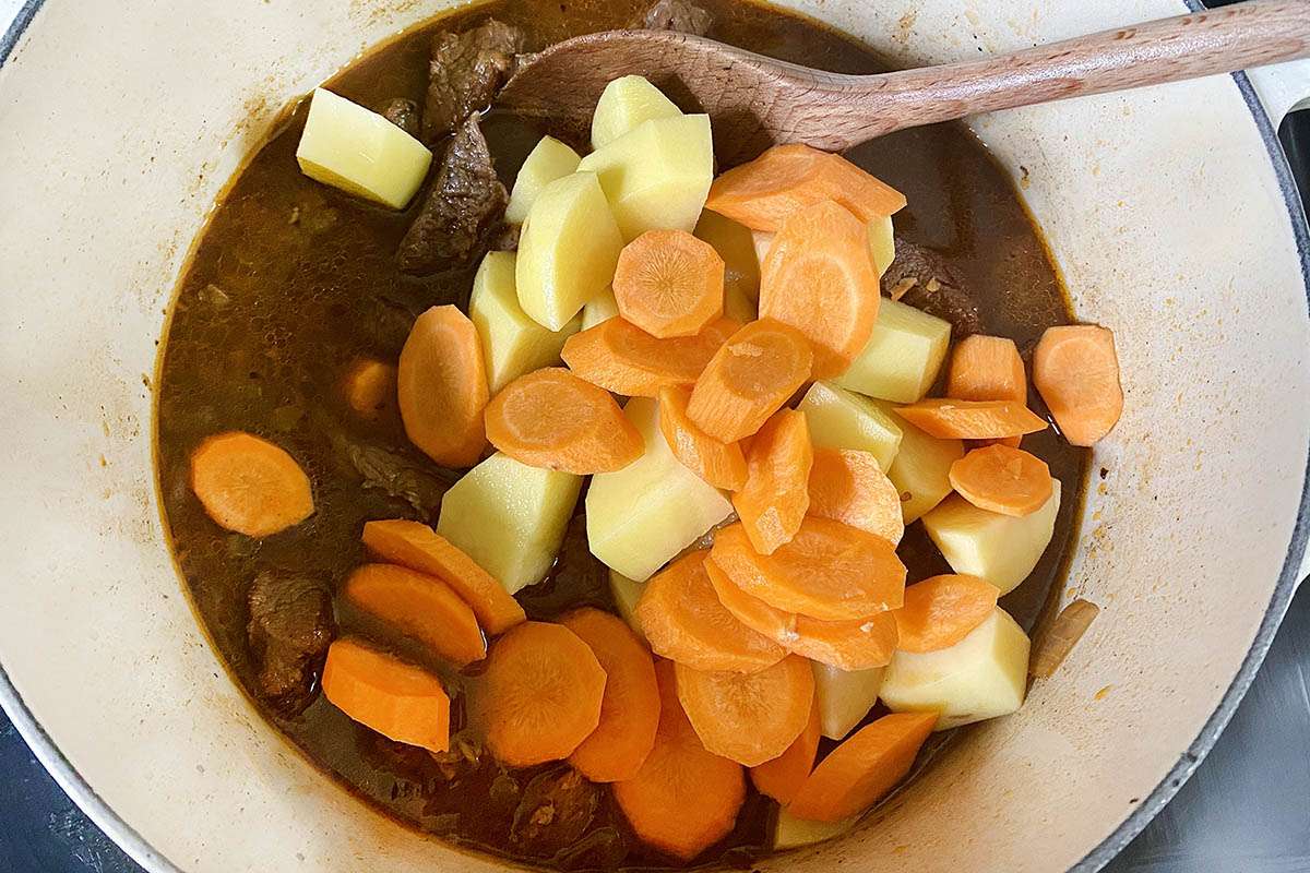 Vegetables added to Jamaican Stewed Beef cooking in a dutch oven.