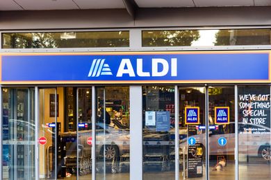 Exterior of an Aldi store entrance with a visible logo and automatic doors