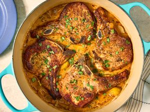 Cooked pork chops in a pot with sauce and garnishes