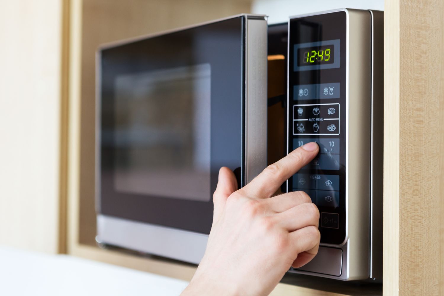 Hand using the touchpad of a microwave oven