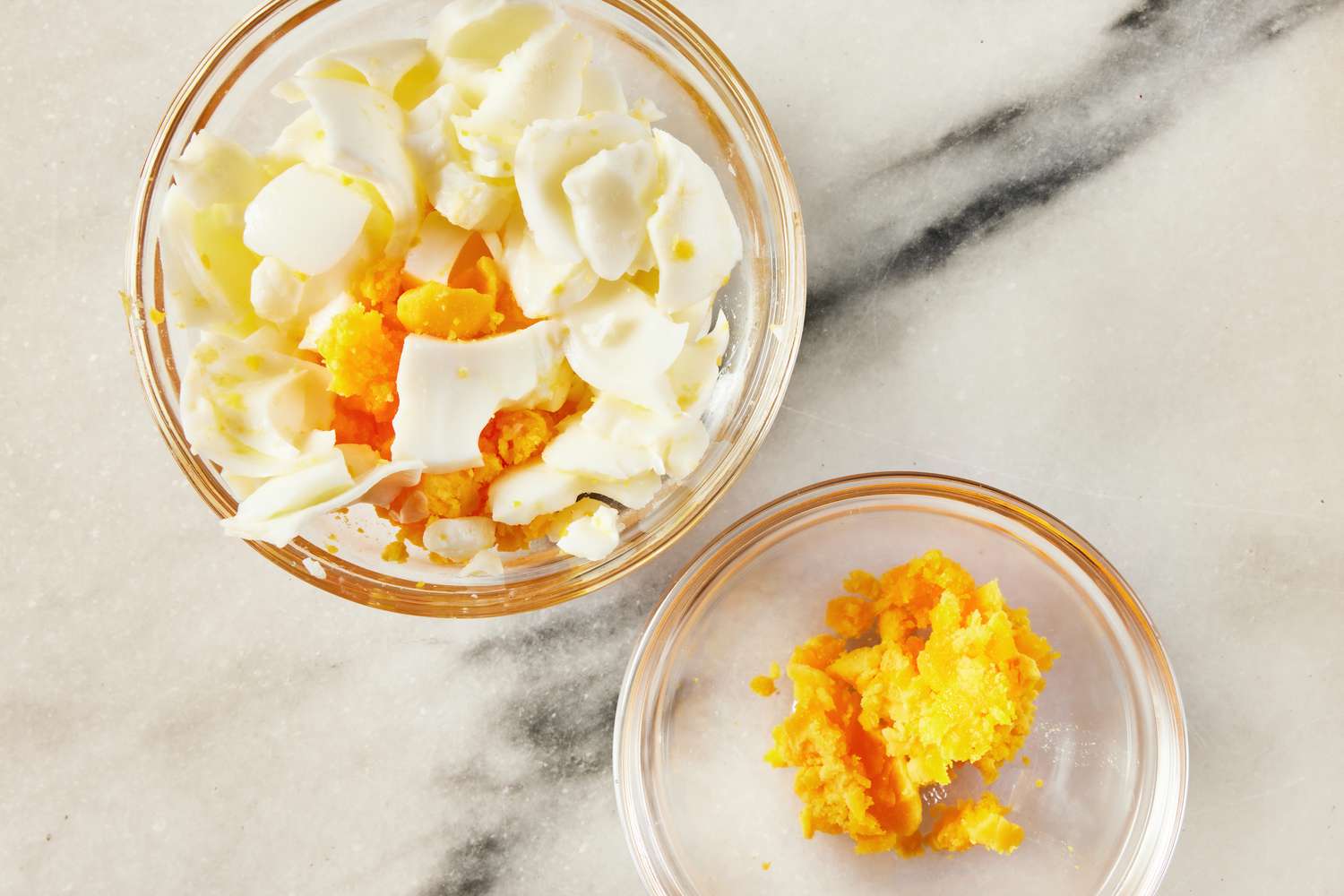 one bowl with boiled egg whites and some egg yokes, another bowl with boiled egg yokes for Korean-style potato salad recipe 