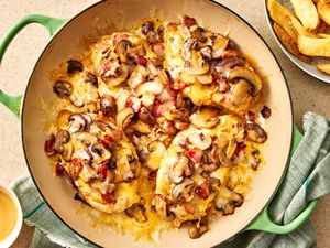 Overhead view of Alice Springs chicken in a braiser next to a plate of steak fries and bowl of honey mustard
