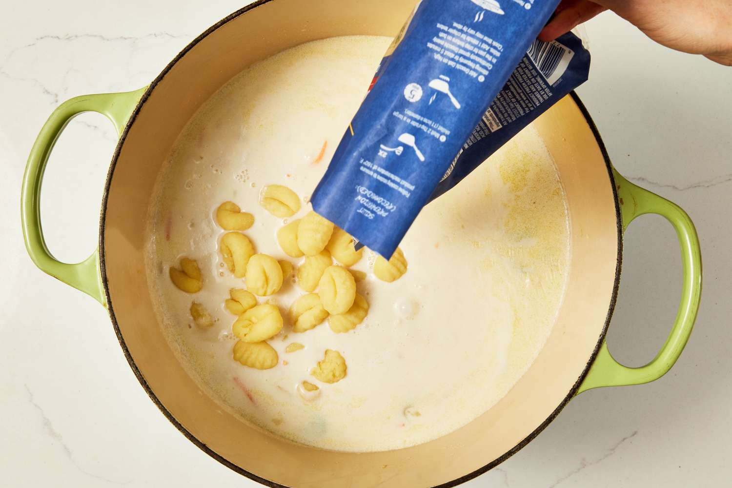 Bag of gnocchi poured into the Dutch oven for copycat Olive Garden chicken and gnocchi soup recipe