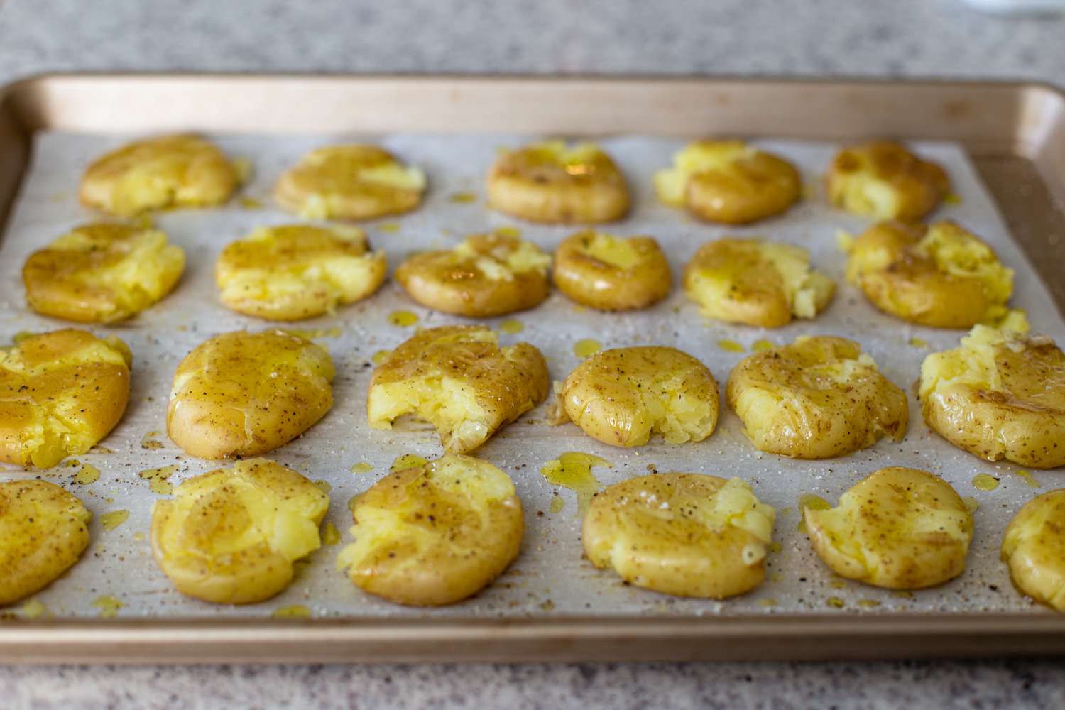 Baked smashed potatoes on a baking sheet for an easy potato appetizer.