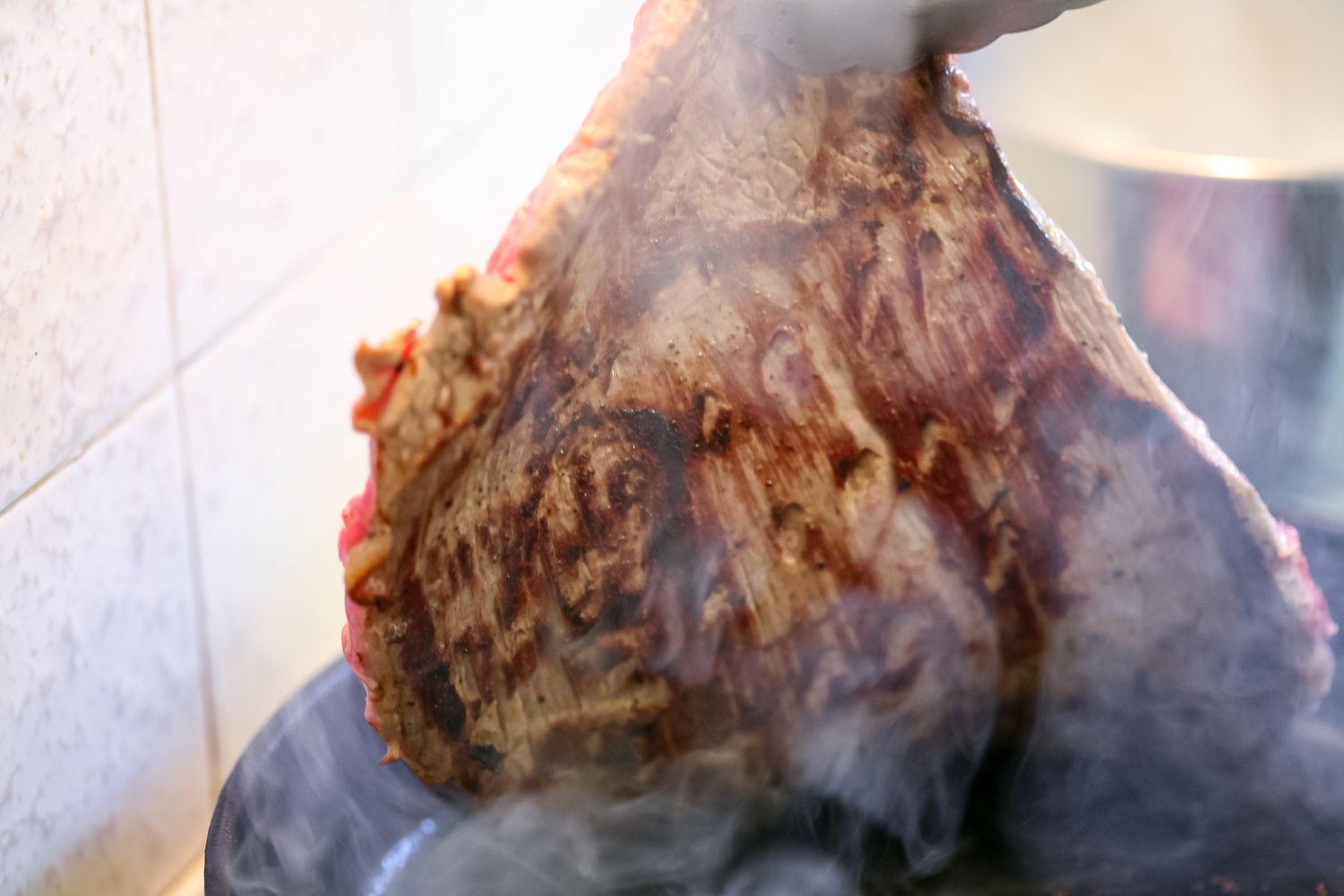 Picking up flank steak from a pan.