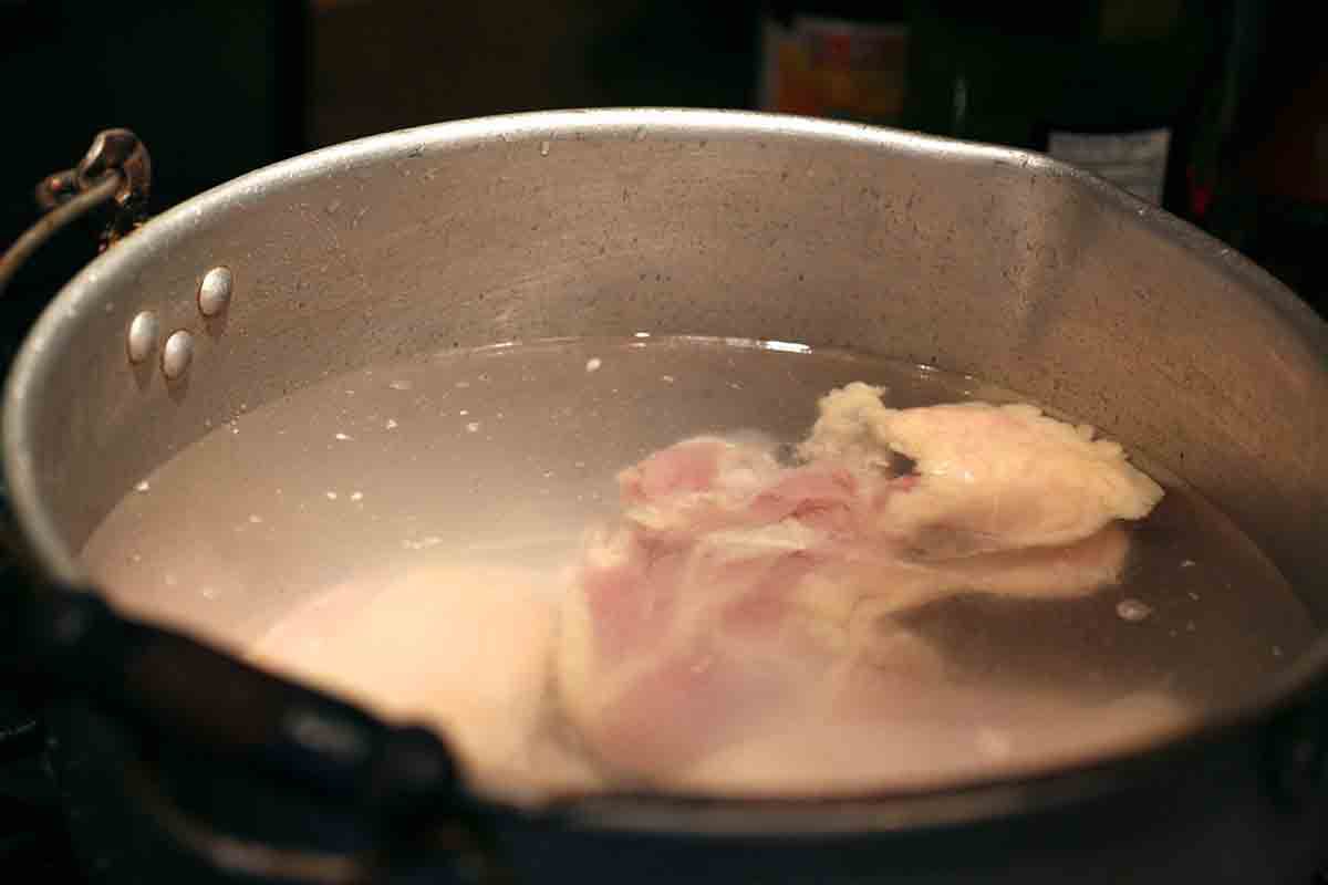 chicken simmering in a pot for pozole