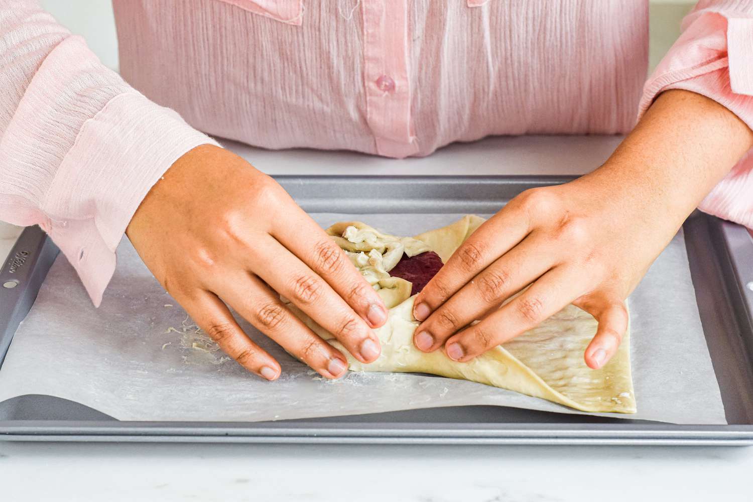 Wrapping brie in puff pastry to make baked brie with jam