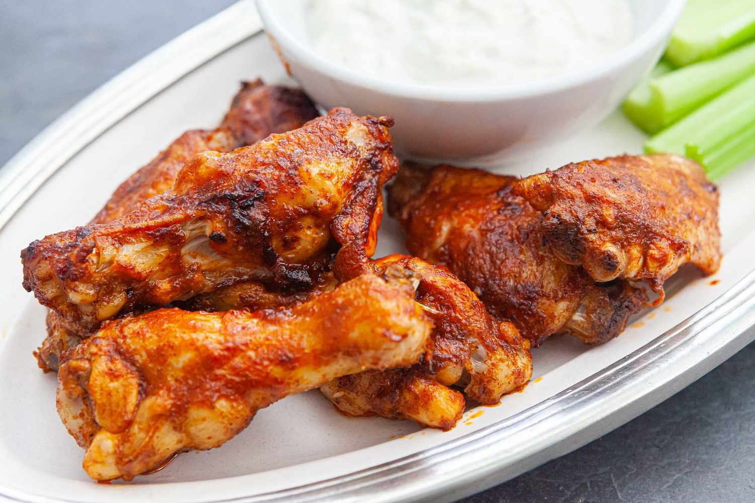 Close up of buffalo wings recipe with blue cheese dressing and celery.