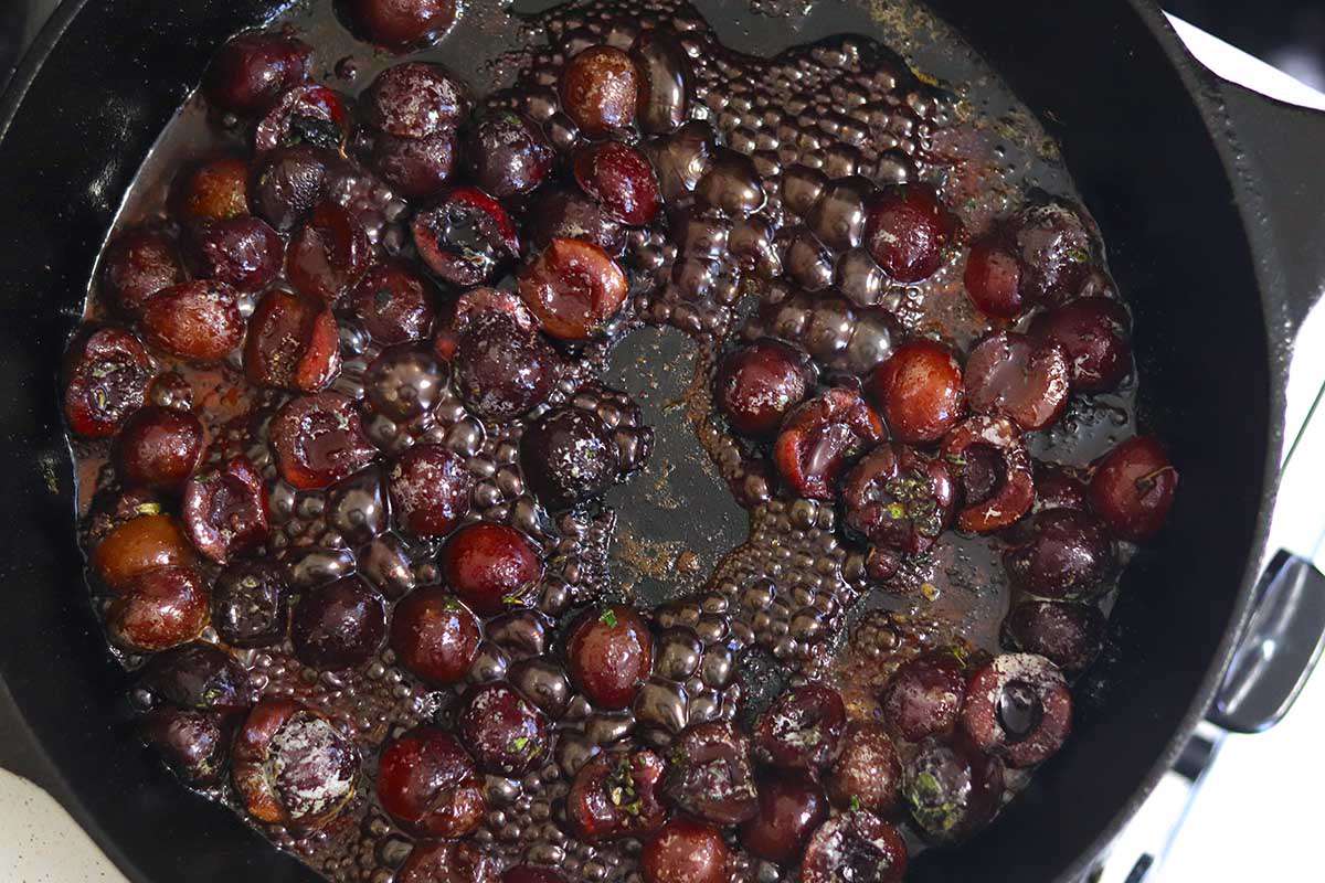 Simmering cherries in a cast iron skillet for stove top pork chops.