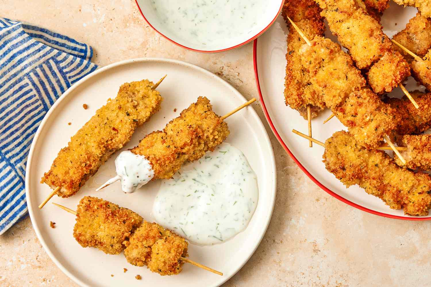 City Chicken, cooked and on skewers on a plate with a creamy sauce on the side