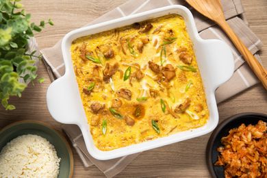 Microwave Oyakodon (Japanese Chicken and Egg Rice Bowl) in a Microwavable Dish Surrounded by a Small Plate With Cooked Rice and a Small Plate of Kimchi
