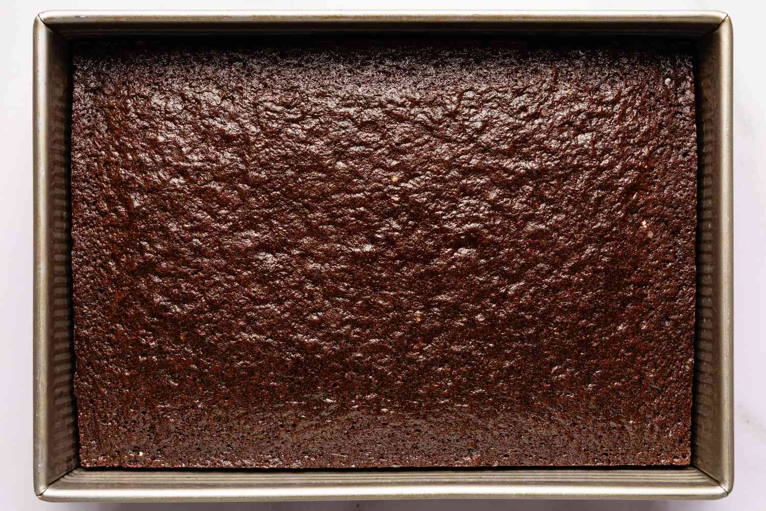 Overhead view of a of the cooked batter mixture in a metal rectangular baking pan for Easy Brooklyn Blackout Cake recipe