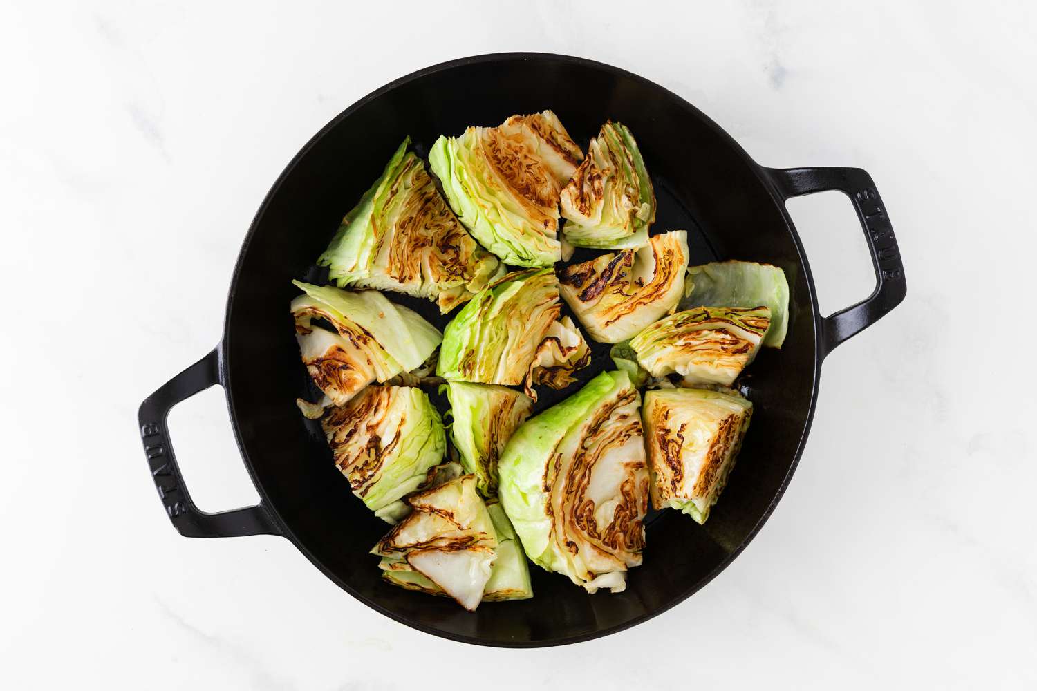 Overhead view of cabbage browning in a cast iron skillet for Cabbage Au Gratin recipe