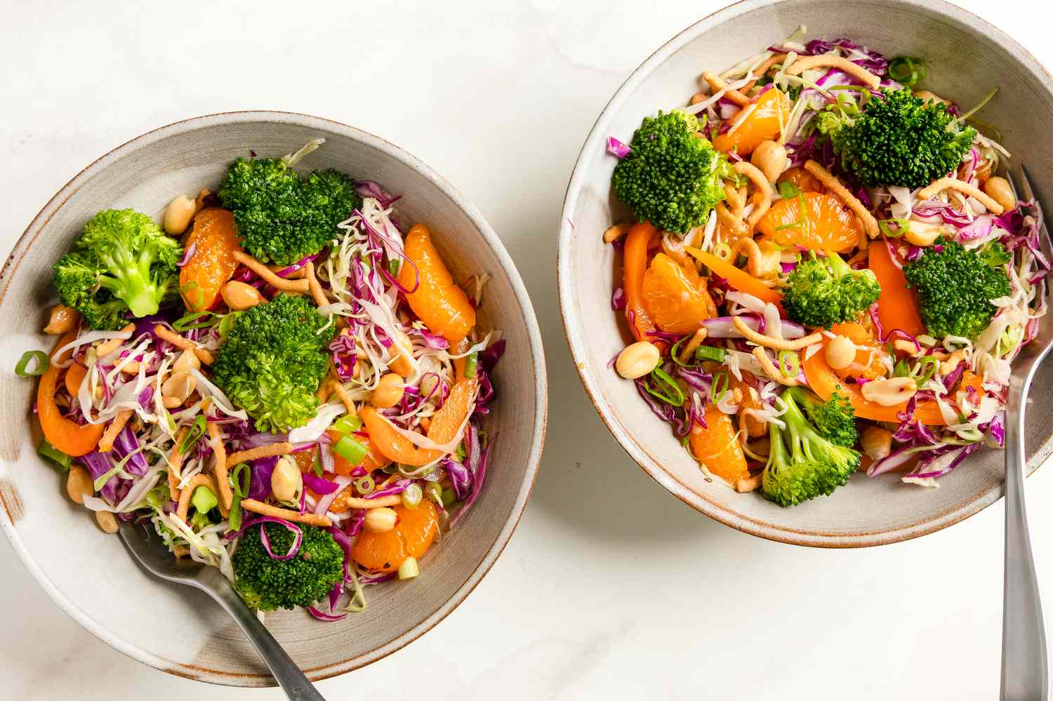 Two bowls of broccoli crunch salad with vegetables and nuts