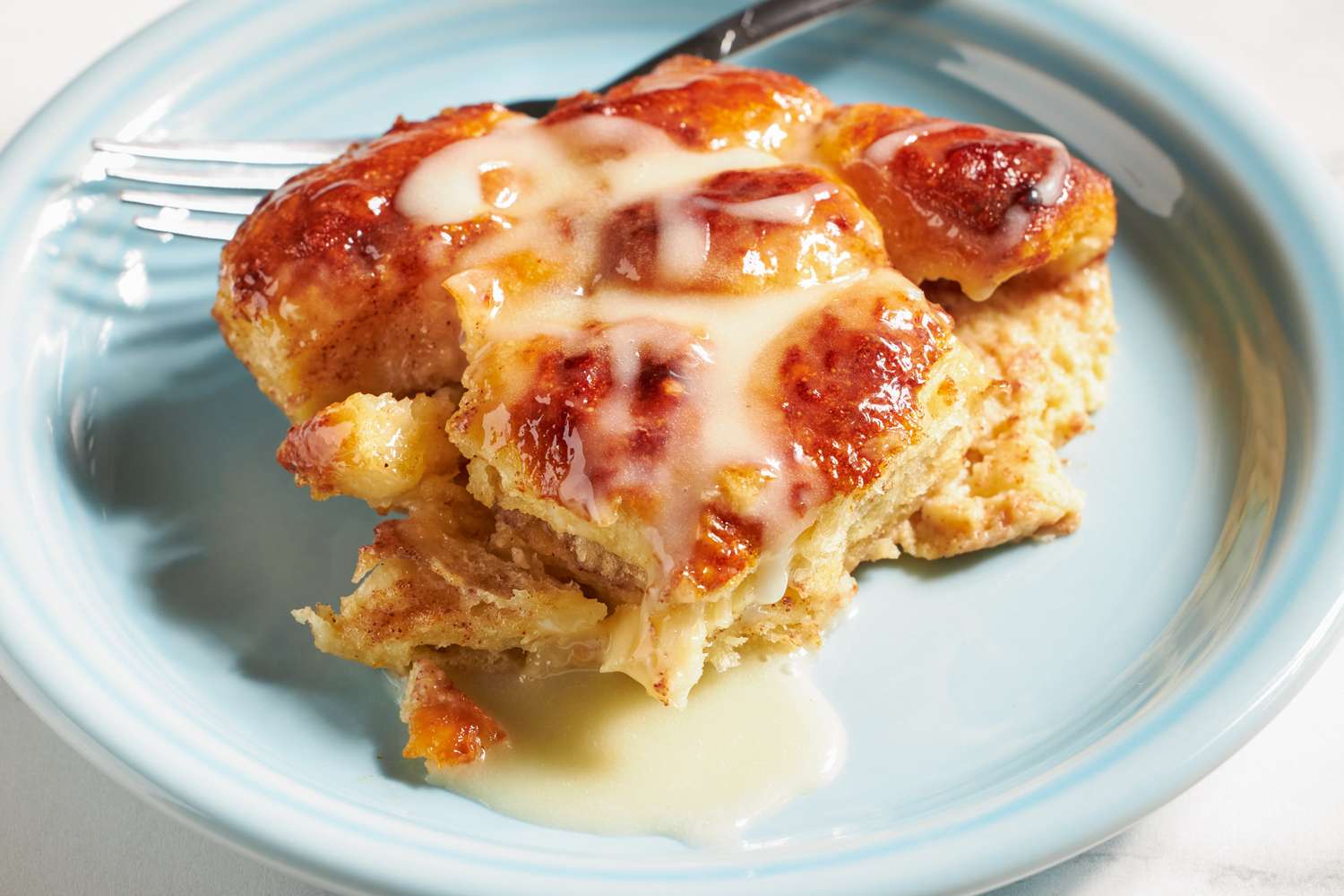 Cinnamon roll bread pudding served on a plate with glaze drizzled on top