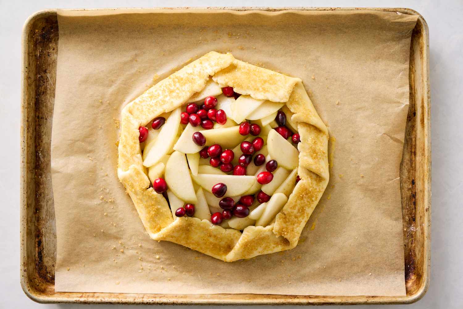 A rustic pear and cranberry galette on a baking sheet lined with parchment paper