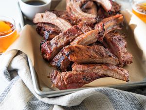 A parchment lined baking sheet with cut ribs from a grilled ribs recipe.