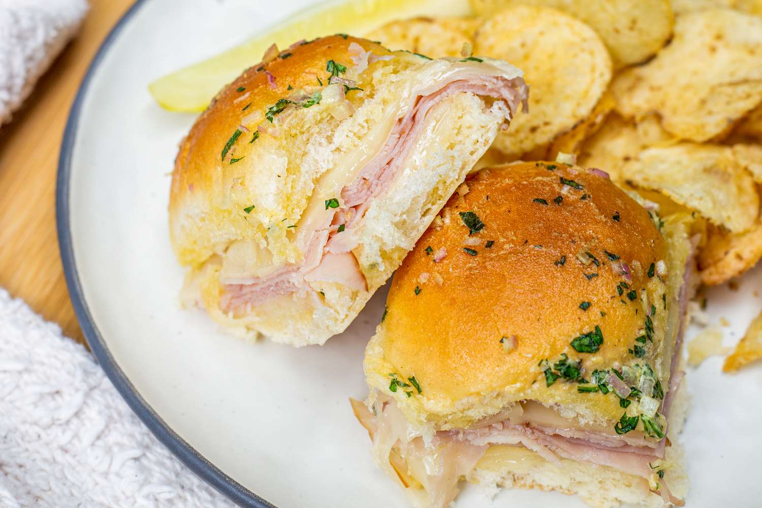 Plate of Hot Ham and Cheese Sandwiches with a Pickle and Chips