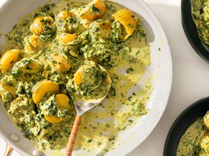 large platter of 5-Ingredient Curried Potatoes with a serving spoon and two bowls on the side