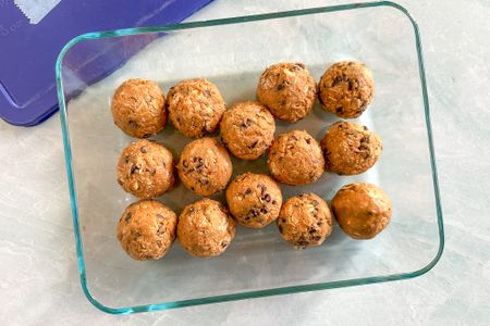 Overhead view of a clear glass bowl of fourteen energy balls on a marble counter