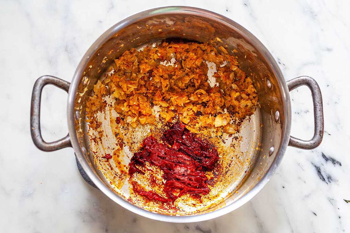 Caramelized onions and tomato paste in the bottom of a soup pot.