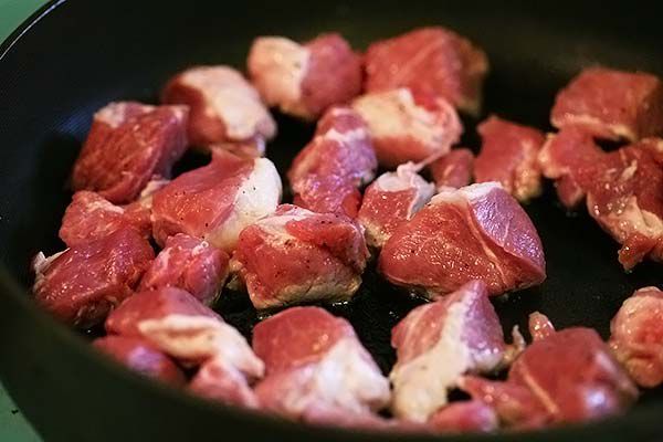 Seasoned pork cubes cooking in a skillet
